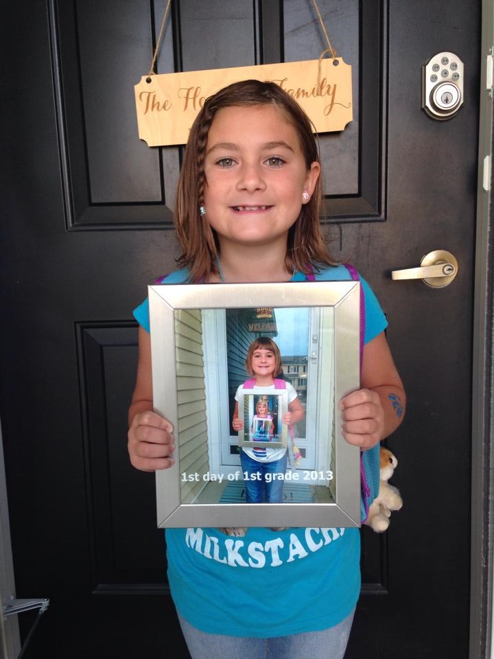 Pornire 2nd grade by holding a pic of what she looked like starting 1st grade.