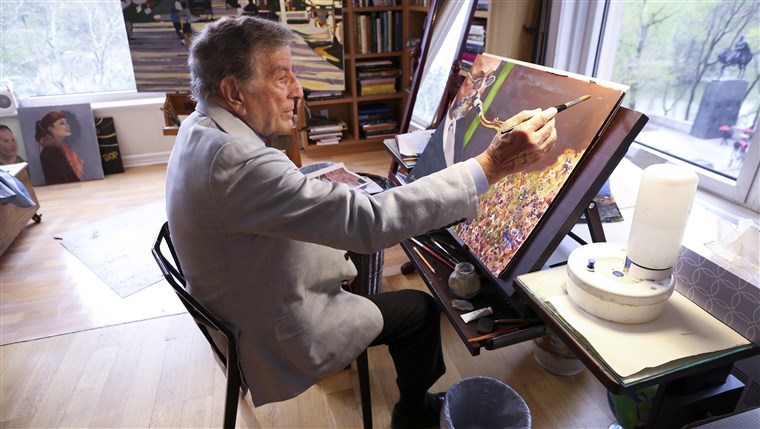 In his New York art studio, Tony Bennett finishes a painting while sitting among several of his completed works. 