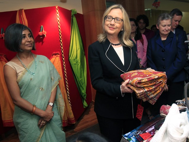 Она might be going easy on the makeup, but she still has an eye for colorful fashion: Clinton holds a sari in Kolkata, India, on May 6.