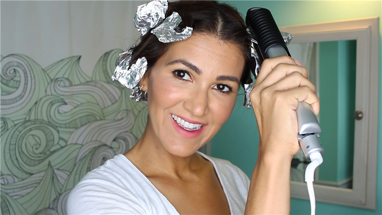 Gnybtas flat iron down on foil to steam hair into bouncy curls.