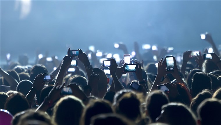 konsert fans hold up cel phones